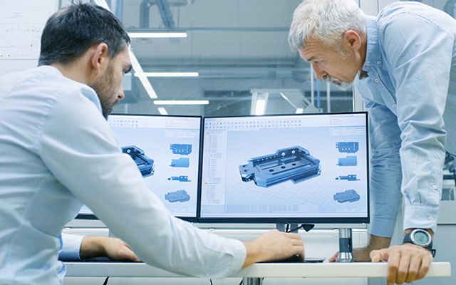 metrologists analyzing CAD model data on a desktop computer