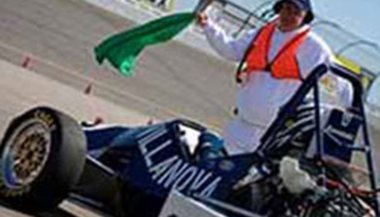 man waving flag in front of race car