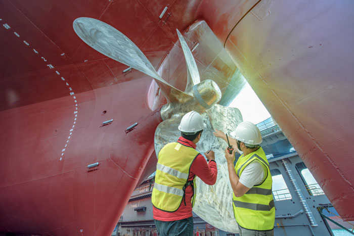 two technicians analyzing the corrosion on a ship's propellor